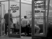 Vintage donut shop with customers inside, featuring signs for coffee and cooper donuts.